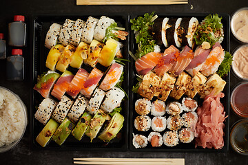 Image showing Asian food delivery home, various sushi sets in plastic containers with sauces, rice and chopsticks