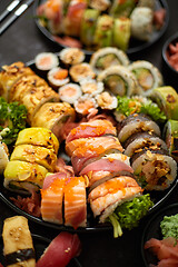 Image showing Assorted sushi set served on dark dark background. Top view of seafood, various maki rolls