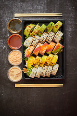 Image showing Asian food delivery home, various sushi sets in plastic containers with sauces, rice and chopsticks