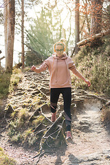 Image showing Active sporty woman running in autumn fall forest jumping over the roots on the path. Healthy lifestyle image of young active caucasian woman jogging outside in nature