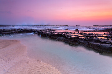 Image showing Pretty sunrise over the beach and rock shelf with reflections