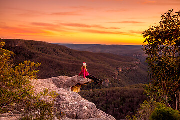 Image showing Hiker sitting on edge of rock precipice with escarpment valley views