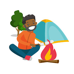 Image showing African man roasting marshmallow over campfire.