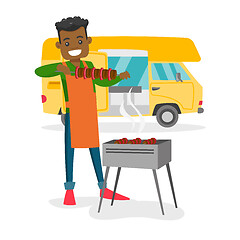 Image showing Young man barbecuing meat in front of camper van.