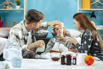 Image showing The young parents with sick daughter at home. The ill family.