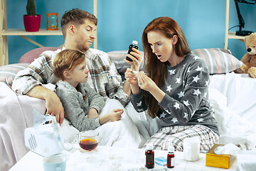 Image showing The young parents with sick daughter at home. The ill family.