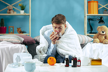 Image showing Bearded sick man with flue sitting on sofa at home. Illness, influenza, pain concept. Relaxation at Home. Healthcare Concepts.