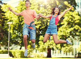 Image showing happy teenage couple jumping at summer park