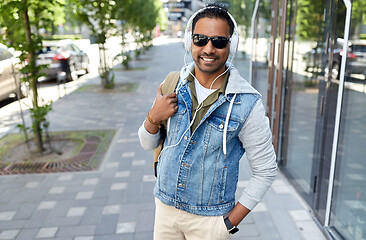 Image showing indian man in headphones with backpack in city