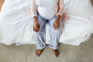 Image showing pregnant african woman sitting on bed at home