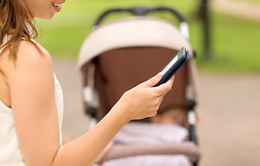 Image showing mother with stroller reading internet book at park