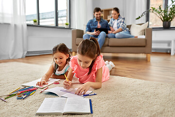 Image showing happy sisters drawing and doing homework at home