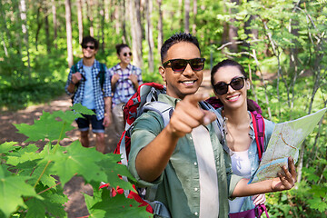 Image showing friends with map and backpacks hiking in forest