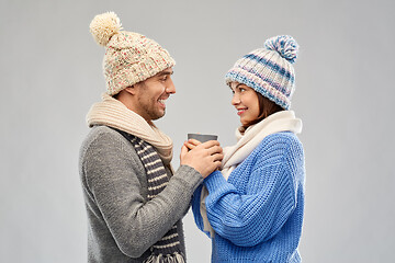 Image showing happy couple in winter clothes holding one cup