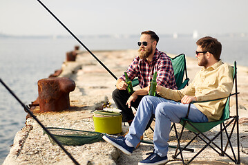 Image showing happy friends fishing and drinking beer on pier