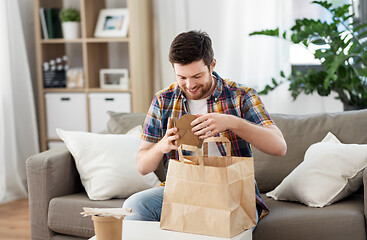 Image showing smiling man unpacking takeaway food at home