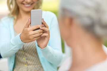 Image showing daughter photographing senior mother by smartphone