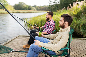 Image showing male friends fishing and drinking beer on lake