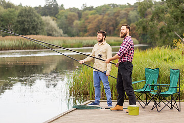 Image showing male friends with fishing rods on lake pier