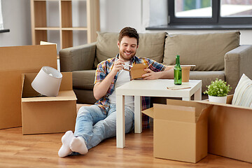 Image showing smiling man eating takeaway food at new home