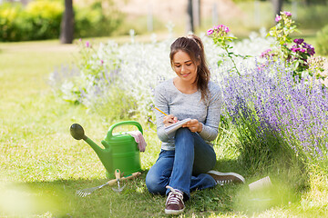 Image showing young woman writing to notebook at summer garden