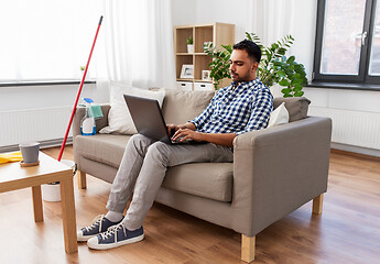 Image showing man with laptop computer after home cleaning