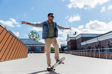 Image showing indian man doing trick on skateboard on roof top