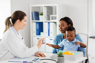 Image showing doctor giving medicine to woman with son at clinic