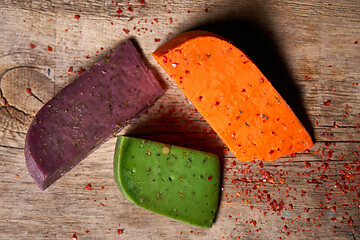 Image showing Three different cheeses on rough wooden planks: lavender, paprika and pesto cheeses