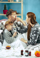 Image showing The young parents with sick daughter at home. The ill family.