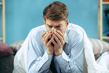 Image showing Bearded sick man with flue sitting on sofa at home. Illness, influenza, pain concept. Relaxation at Home. Healthcare Concepts.