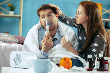 Image showing Sick man with fever lying in bed having temperature girl take care for him