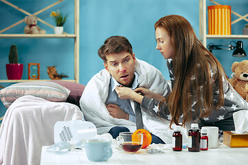 Image showing Sick man with fever lying in bed having temperature girl take care for him