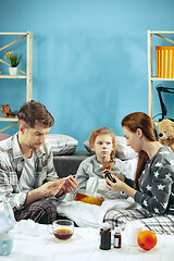 Image showing The young parents with sick daughter at home. The ill family.