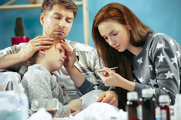 Image showing The young parents with sick daughter at home. The ill family.