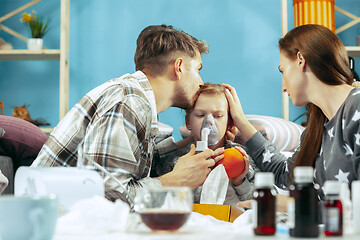 Image showing The young parents with sick daughter at home. The ill family.