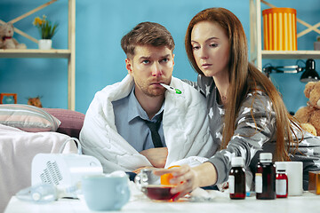 Image showing Sick man with fever lying in bed having temperature girl take care for him