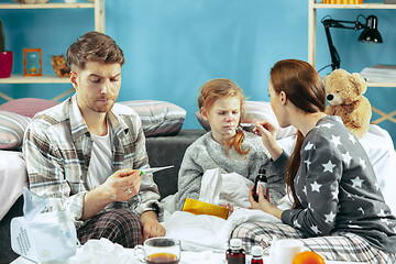 Image showing The young parents with sick daughter at home. The ill family.