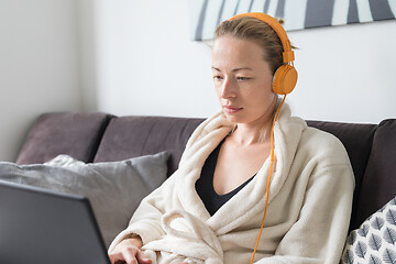 Image showing Stay at home, shelter in place and social distancing. Woman in her casual home bathrobe relaxing while working remotly from her living room. Using social media apps for video chatting.