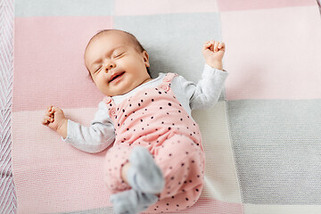 Image showing sleeping baby girl in pink suit lying on blanket