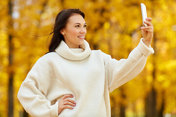 Image showing woman taking selfie by smartphone at autumn park