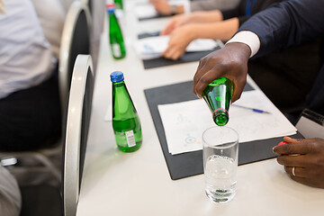 Image showing businessman pouring water to glass at conference