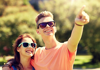 Image showing happy couple pointing finger at summer park