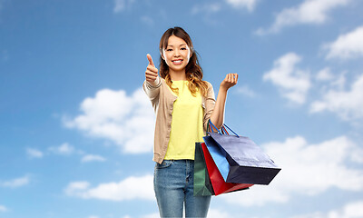 Image showing asian woman with shopping bags showing thumbs up