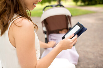 Image showing mother with stroller reading internet book at park