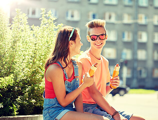 Image showing happy teenage couple eating hot dogs in city