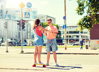 Image showing teenage couple riding skateboards on city street