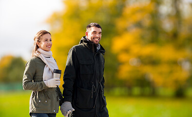 Image showing couple with tumbler walking along autumn park