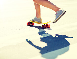 Image showing male legs riding short skateboard along crosswalk