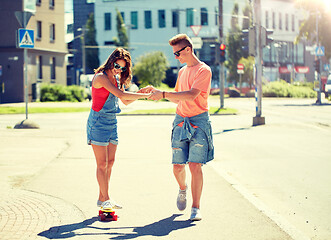 Image showing teenage couple riding skateboards on city street